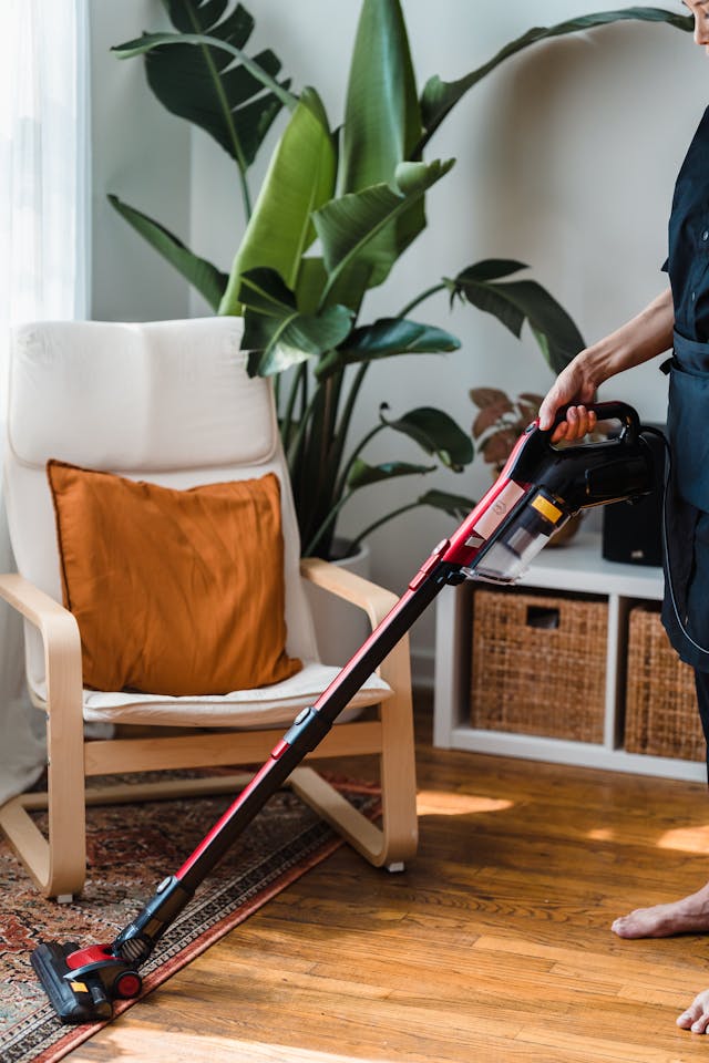 A woman vacuuming a hardwood floor, demonstrating effective cleaning techniques in a tidy living space.