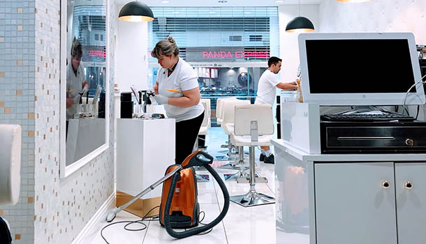 A woman is using a vacuum cleaner to clean a room, focusing on maintaining a tidy environment.